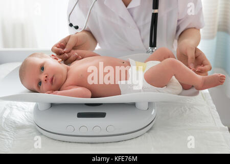 Primo piano di Un medico che verifica il peso di carino bambino piccolo Foto Stock