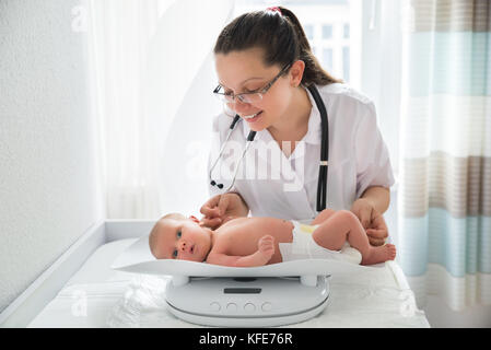 Felice pediatra femmina di controllo del peso del simpatico baby Foto Stock