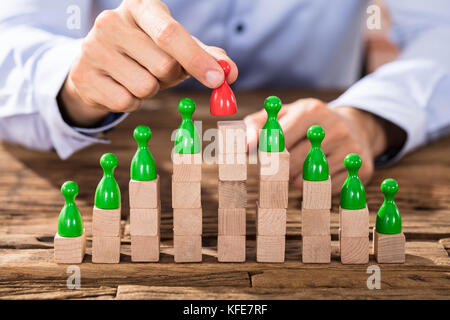 Close-up di un imprenditore immissione rosso leader figura su blocchi disposti sopra la scrivania in legno Foto Stock