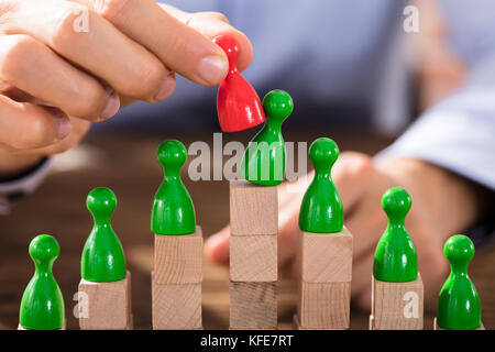 Imprenditore sostituisce il verde la figura con il rosso figura sulla parte superiore dei blocchi di legno Foto Stock