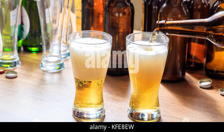 Versare la birra in un pupazzo di neve con un bicchiere di birra su un sfondo di pub Foto Stock