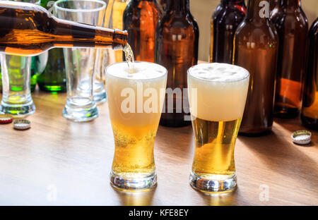 Versare la birra in un pupazzo di neve con un bicchiere di birra su un sfondo di pub Foto Stock