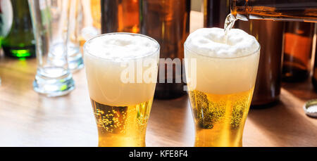 Versare la birra in un pupazzo di neve con un bicchiere di birra su un sfondo di pub Foto Stock