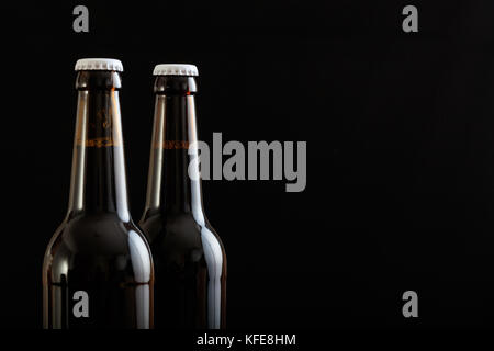 Primo piano di due aperti di bottiglie di birra isolato su sfondo nero Foto Stock