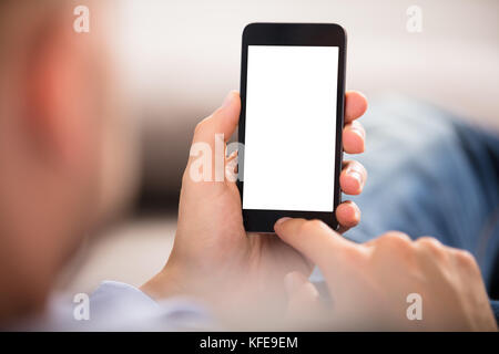 Close-up di una mano di un uomo Azienda Telefono cellulare con il bianco schermo vuoto Foto Stock