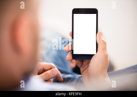 Close-up di una mano di un uomo Azienda Telefono cellulare con il bianco schermo vuoto Foto Stock