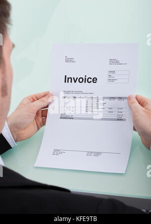 Immagine ritagliata del giovane imprenditore fattura di lettura alla scrivania in ufficio Foto Stock