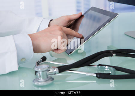 Immagine ritagliata del giovane maschio medico utilizzando digitale compressa al banco in clinica Foto Stock