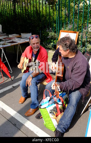 2 titolari di stallo suonare la chitarra al Marche aux Puces mercato delle pulci di Porte de Vanves a Parigi in una Domenica mattina Foto Stock