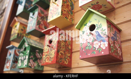 Case colorate per uccelli. Casa per uccelli in legno fatta a mano su una casa di tronchi. Case per uccelli sul muro. Quartiere. Birdhouse in legno in stile vintage Foto Stock