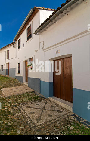 Vicolo di ciottoli - con disegni tradizionali davanti alle porte chiamato 'llanos', Linares de la Sierra, provincia di Huelva, regione dell'Andalusia, Spagna, EUR Foto Stock