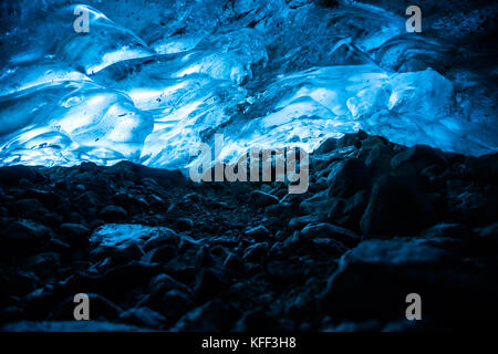 In uno stretto tunnel sotto un ghiacciaio in British Columbia, Canada, il ghiaccio al di sopra si illumina di blu dal sole che splende attraverso strati di ghiaccio sopra. Foto Stock