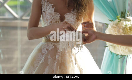 Primo piano di una sposa che mette una fede nuziale d'oro sul dito dello sposo. fedi nuziali e mani di sposa e sposo. giovane coppia di nozze alla cerimonia. anello antiusura della sposa sul dito dello sposo. Foto Stock