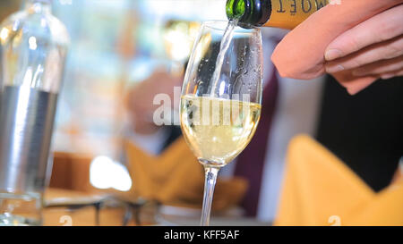 Versare lo champagne in un bicchiere. Barman che versa champagne nel bicchiere, primo piano. Champagne in bicchiere Foto Stock