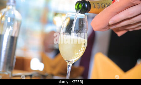 Versare lo champagne in un bicchiere. Barman che versa champagne nel bicchiere, primo piano. Champagne in bicchiere Foto Stock