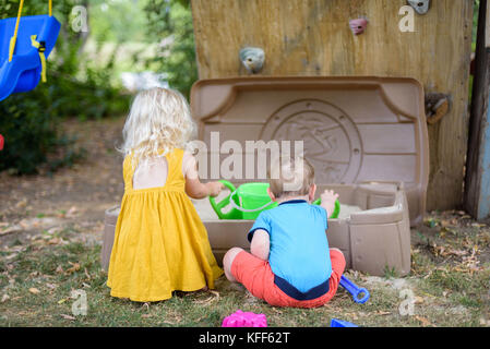 Due piccoli bambini che giocano in cortile sandbox in estate Foto Stock