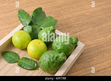 Vegetali e le erbe, combava persiano con lime e foglie di kaffir per la stagionatura in cottura su vassoio in legno Foto Stock