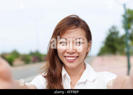 Asian giovane ragazza tenendo selfie foto belle sorridenti immagine di donna Foto Stock