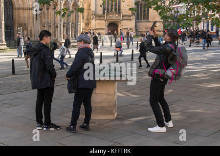 L uomo si prende la foto con il telefono come turisti stand in York centro piazza dal modello di Minster area, Cathedral & persone al di là - North Yorkshire, Inghilterra, Regno Unito. Foto Stock