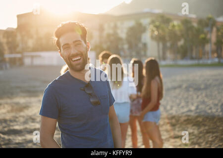 Ritratto di uomo bello ridere con gli amici dietro di lui Foto Stock
