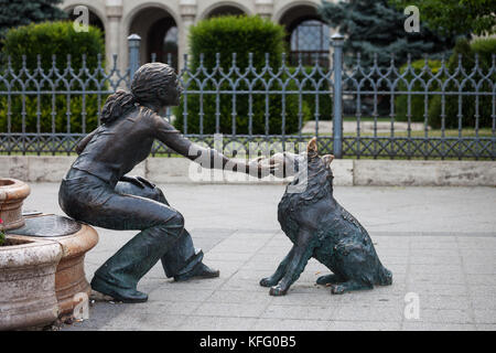 Ragazza con il suo cane, street scultura in bronzo, piazza Vigado, città di Budapest, Ungheria, ragazza giocare con l'animale con la sfera nella sua bocca Foto Stock