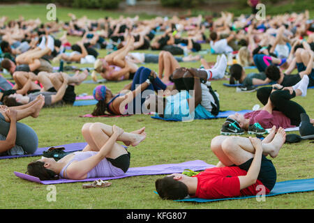 Atlanta, GA, Stati Uniti d'America - 2 luglio 2, 2017: decine di persone fanno il vento pongono in esecuzione sulle loro spalle come essi prendono parte in un gruppo libero yoga classe in Atlanta. Foto Stock