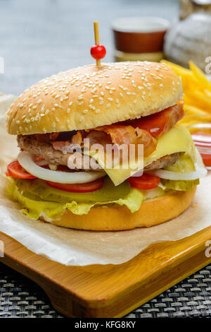 Formaggio hamburger con bakon guarnita con salse e patate fritte Foto Stock