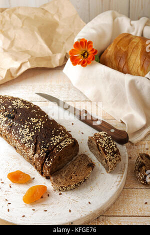 Pagnotta e fette di pane azzimo di segale senza lievito con albicocche secche e uva passa cosparse di semi di lino e di sesamo Foto Stock