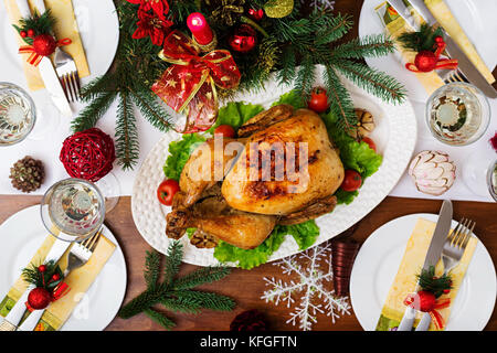 La Turchia al forno o pollo. la tavola del Natale è servita con una Turchia, decorate con colori luminosi tinsel e candele. pollo fritto, tabella. Cena di Natale Foto Stock