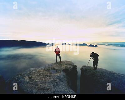 Sagome di uomo fotografi. gli uomini sulla montagna. picco con due uomini di scattare le foto in autunno alba Foto Stock