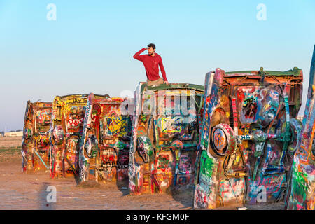 Amarillo, Texas, Stati Uniti. 18 ottobre 2015. Un uomo adulto guarda la vista dalla cima delle auto sepolte al Cadillac Ranch Foto Stock