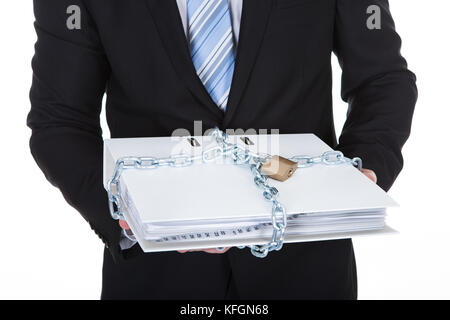 Imprenditore tenendo un top secret file confidenziali bloccato con una catena e un lucchetto per impedire accessi non autorizzati isolato su bianco Foto Stock