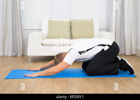 Ritratto di giovane uomo fare esercizio sul tappeto blu Foto Stock