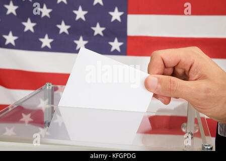 Primo piano di una persona in Front American Flag che mette il ballottaggio in scatola di vetro Foto Stock