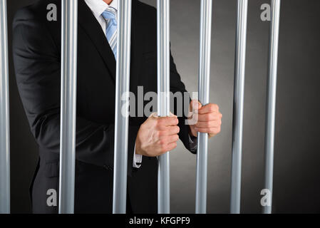 Primo piano dell'uomo d'affari in Jail Holding barre metalliche Foto Stock