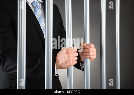 Primo piano dell'uomo d'affari in Jail Holding barre metalliche Foto Stock