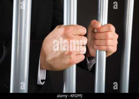 Primo piano di businessman Hand Holding Metal Bar in prigione Foto Stock