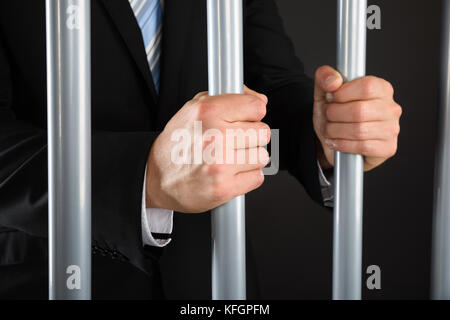 Primo piano di businessman Hand Holding Metal Bar in prigione Foto Stock