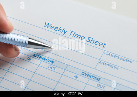 Primo piano della mano della persona con penna su foglio presenze settimanale vuoto Foto Stock
