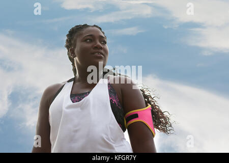 Attraente sportivo donna africana in sport clothers guardando lontano sul cielo blu sullo sfondo Foto Stock