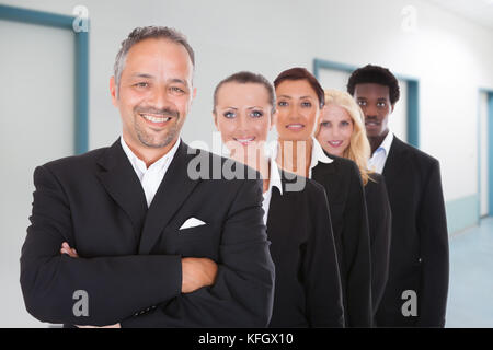 Ritratto di felice imprenditori multietnica in piedi in una fila in ufficio Foto Stock
