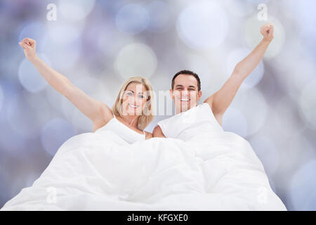 Ritratto di coppia riuscita con le braccia sollevate sul letto Foto Stock