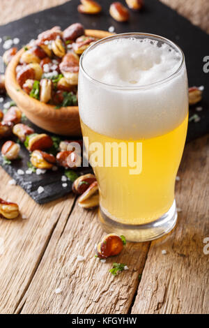 Birra leggera o birra light spumosi e fritti salati fave vicino sul piano verticale. Foto Stock