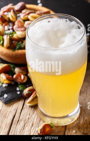 Birra leggera o birra light con schiuma e fritti salati fave vicino sul piano verticale. Foto Stock