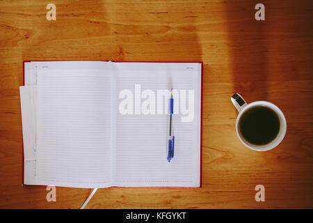 Notebook rosso e la tazza di caffè su una scrivania in ufficio Foto Stock