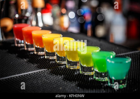 Una fila di duri colpi alcolica nei colori dell'arcobaleno servita sul bancone del bar Foto Stock