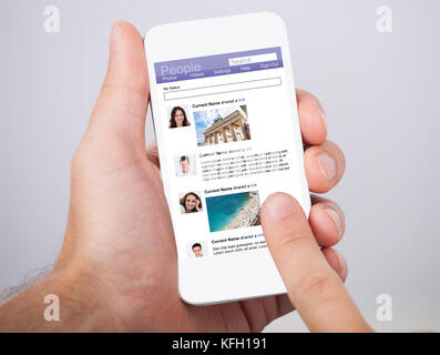Primo piano della mano d'uomo tenendo lo smartphone con il sito sociale visualizzati sullo schermo Foto Stock