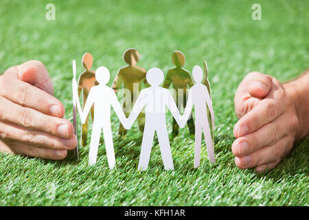 Primo piano delle mani del team di protezione di carta di persone sul campo erboso Foto Stock