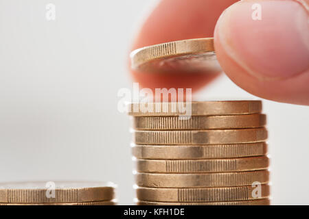 Immagine ritagliata di imprenditore a mano delle monete di impilamento in office Foto Stock