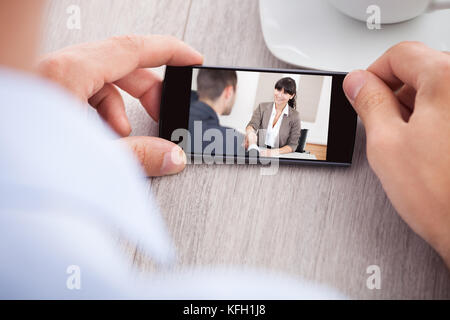Immagine ritagliata di imprenditore guardando film a tavola in office Foto Stock